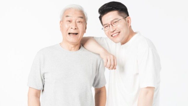 一位面帶笑容的長者與年輕家人合照，圖片下方有橙色標題寫著「長者應如何選購助聽器」。這張圖片用於說明長者在家人陪同下，應諮詢專業意見以挑選合適的助聽器。Heari 傾耳聽 香港聽力中心 | 立即登記免費聽力測試